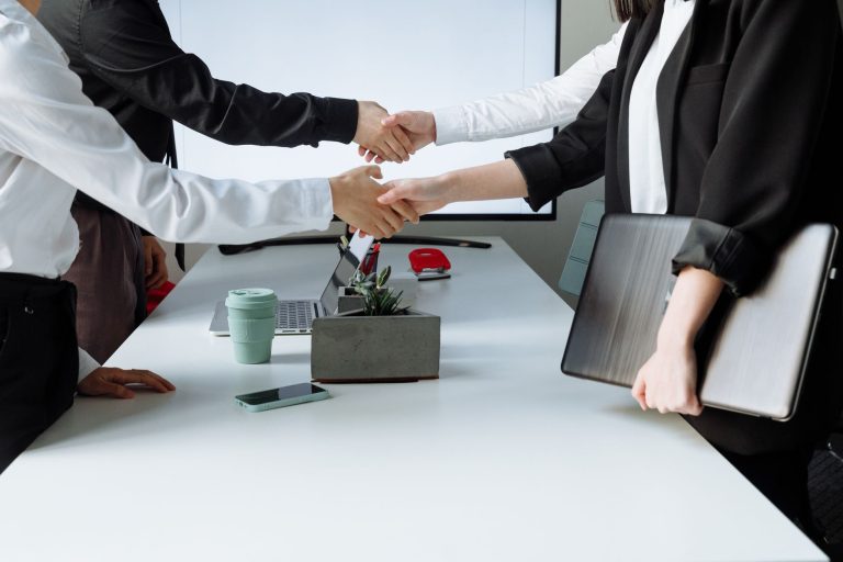Professionals sealing a deal with a handshake across a conference table during a business meeting. — Important Tips to Consid