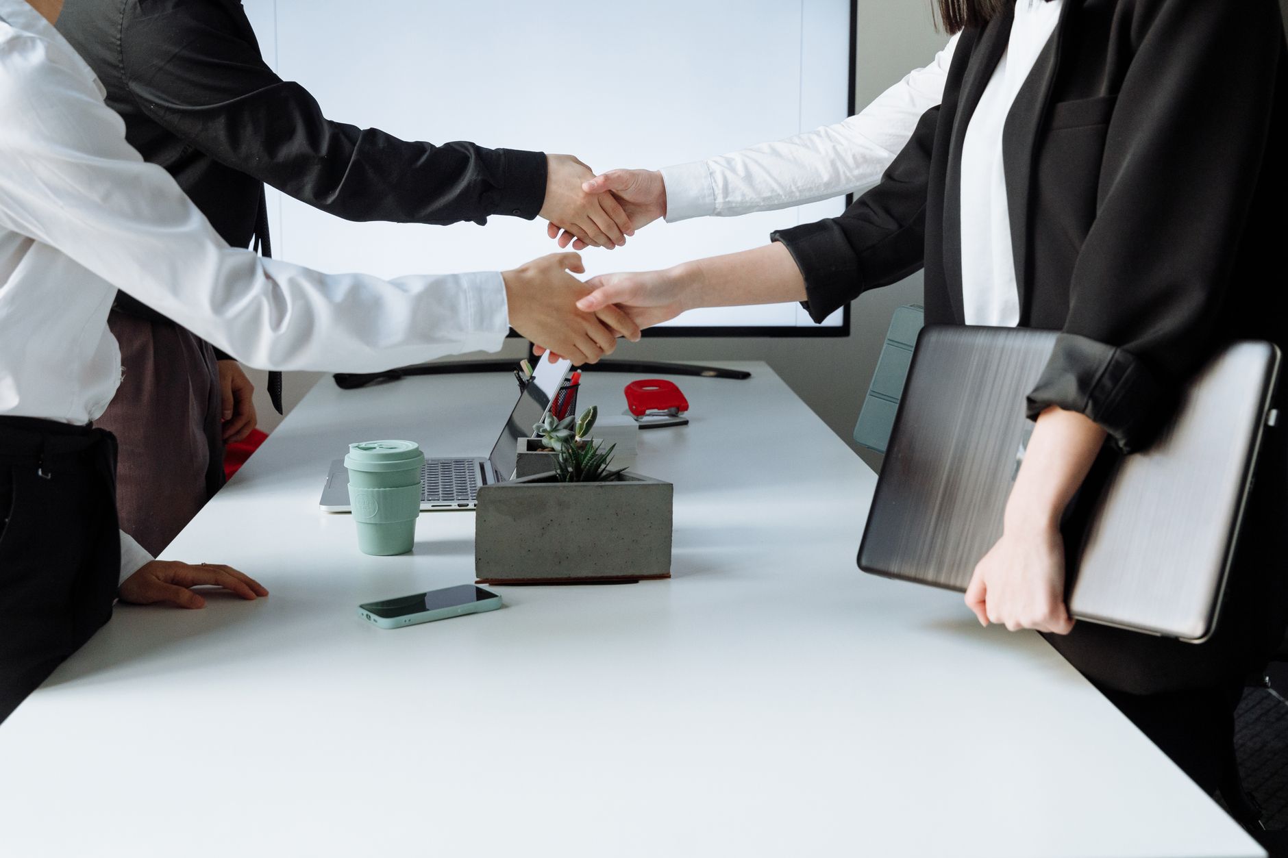 Professionals sealing a deal with a handshake across a conference table during a business meeting. — Important Tips to Consid