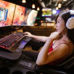 Young woman in red top gaming on dual monitors with white headphones in a modern setup. — Incredible facts that will tend you