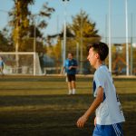 A teenager plays soccer outdoors on a sunny day, enjoying friendly competition. — IPL Fantasy Betting Tips: Five Batsmen duri