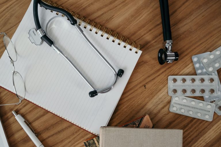 Flat lay of medical tools and supplies on a wooden desk surface. — Is covid 19 confirmed through PCR testing?