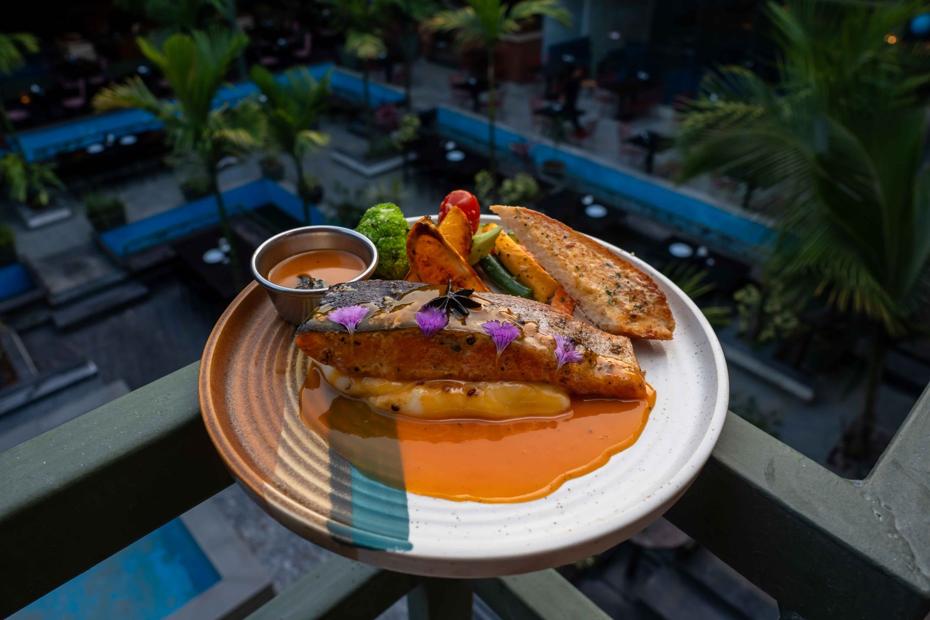 A beautifully plated salmon dish with vegetables and sauce served al fresco, highlighting vibrant culinary presentation. — Is