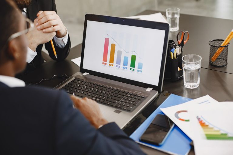 Two professionals analyzing a business graph on a laptop during a meeting. — Is It Worth Trying a Yes or No Tarot Reading?