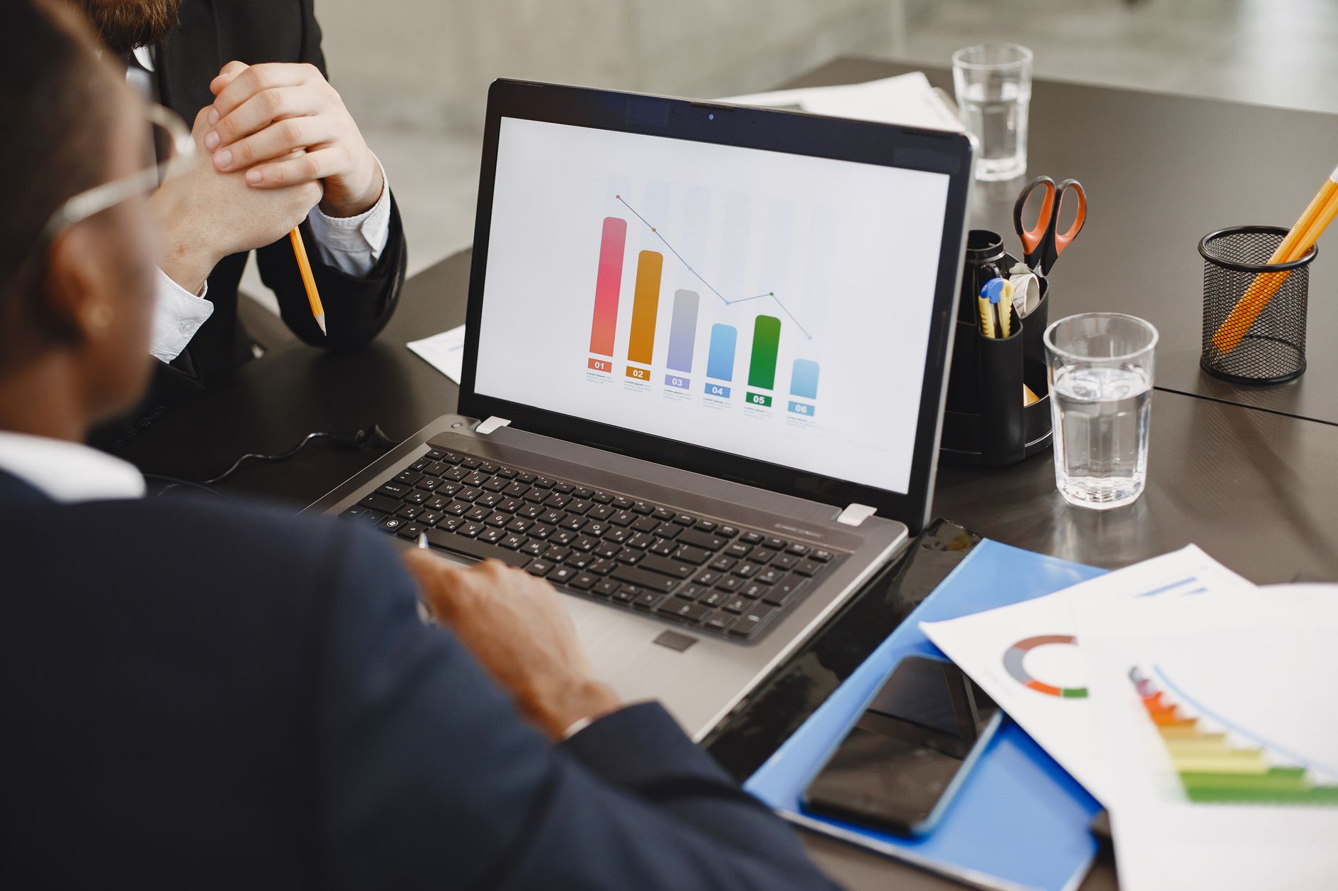 Two professionals analyzing a business graph on a laptop during a meeting. — Is It Worth Trying a Yes or No Tarot Reading?