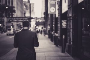Man in a suit walking down a city street in a lonely, urban setting. — Legal Neuroscience and Imaging Research by Dr. Andrew
