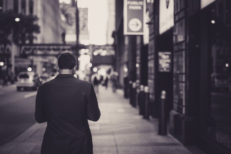 Man in a suit walking down a city street in a lonely, urban setting. — Legal Neuroscience and Imaging Research by Dr. Andrew
