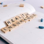 Scrabble tiles spelling 'Health Insurance' on a calendar with pills. — Medicare Advantage Plans and Comparison Methods