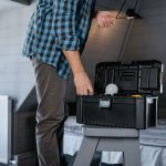 Person in plaid shirt fixing a light bulb using a toolbox in a rustic attic interior. — Parasols and buyer guide to their acc