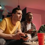 Diverse group of young adults playing video games on a cozy sofa with refreshments. — Play with Confidence at Macau Online Ca