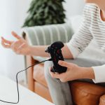 Close-up of a person playing video games at home with a wired controller on a couch. — Playing 8 ball with Gamezy