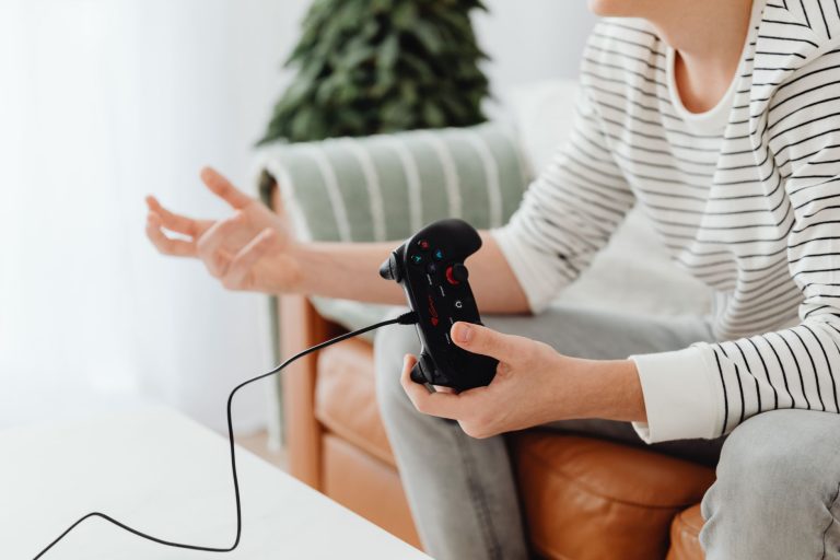 Close-up of a person playing video games at home with a wired controller on a couch. — Playing 8 ball with Gamezy