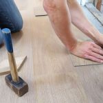 A craftsman carefully measures and marks wooden floor panels for precise installation. — Read this to know how you can be mor