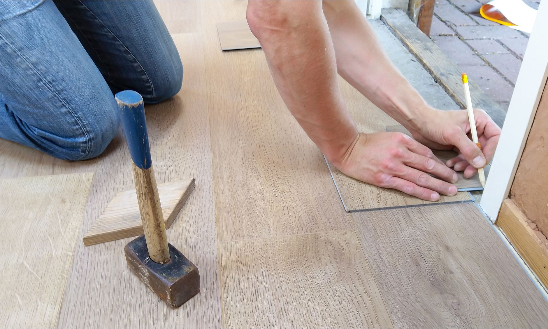 A craftsman carefully measures and marks wooden floor panels for precise installation. — Read this to know how you can be mor