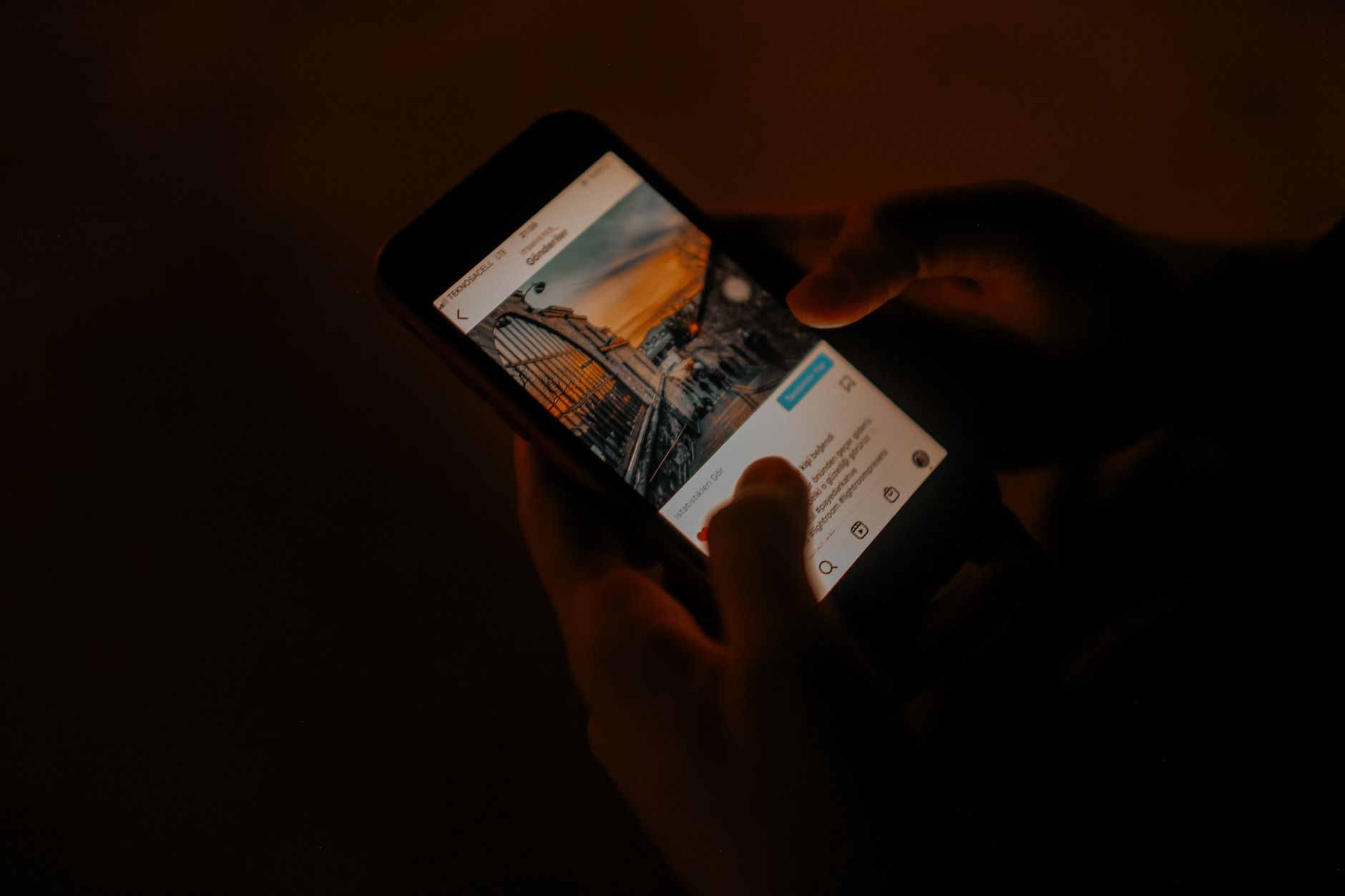 Hands holding a smartphone browsing social media in low light. — Save Time and Resources by Leveraging a Facebook Ads Agency