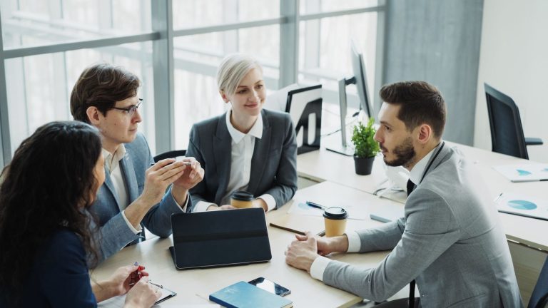 Group of professionals having a discussion in a modern office setting with natural light. — Spacious Beachfront Home Under $2
