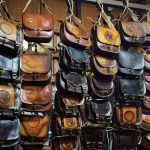 A collection of handcrafted leather bags with artistic designs on display at a shop. — Feel Refreshed And Revitalized
