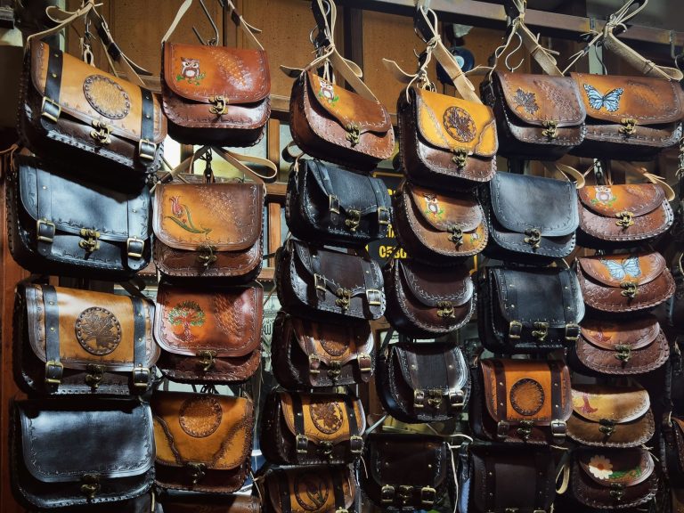 A collection of handcrafted leather bags with artistic designs on display at a shop. — Feel Refreshed And Revitalized