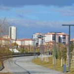An empty urban park pathway lined with trees, lampposts, and modern residential buildings. — Get Ready to Win: Tips o