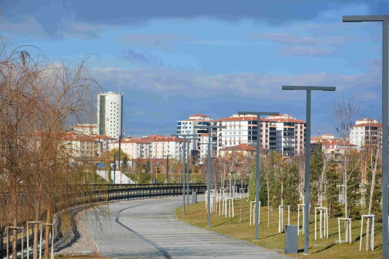 An empty urban park pathway lined with trees, lampposts, and modern residential buildings. — Get Ready to Win: Tips o