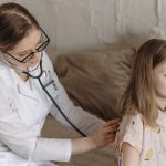 A doctor with a stethoscope examining a smiling girl during a medical check-up at home. — Stylish Bongs With Superb Glass Qua
