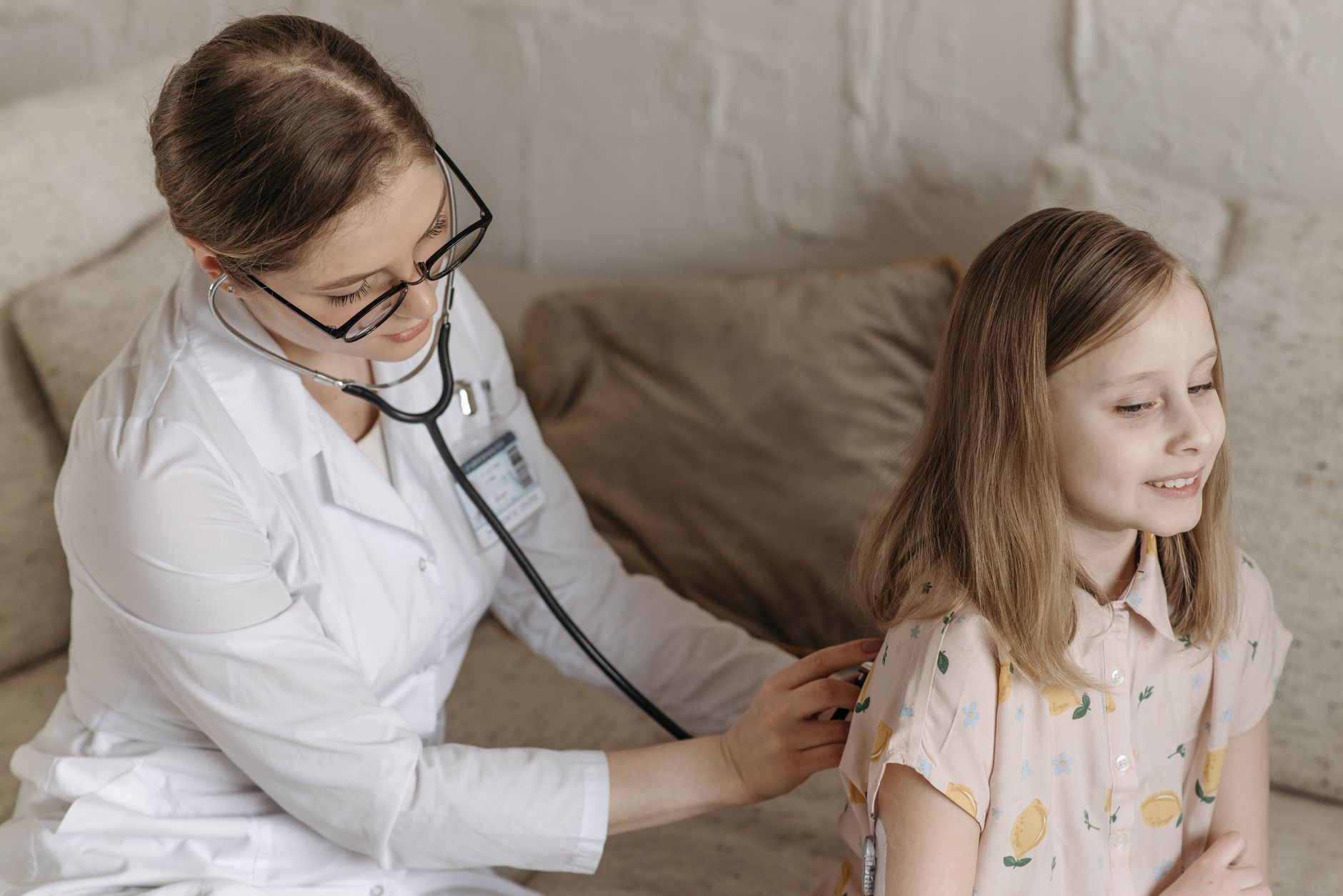 A doctor with a stethoscope examining a smiling girl during a medical check-up at home. — Stylish Bongs With Superb Glass Qua