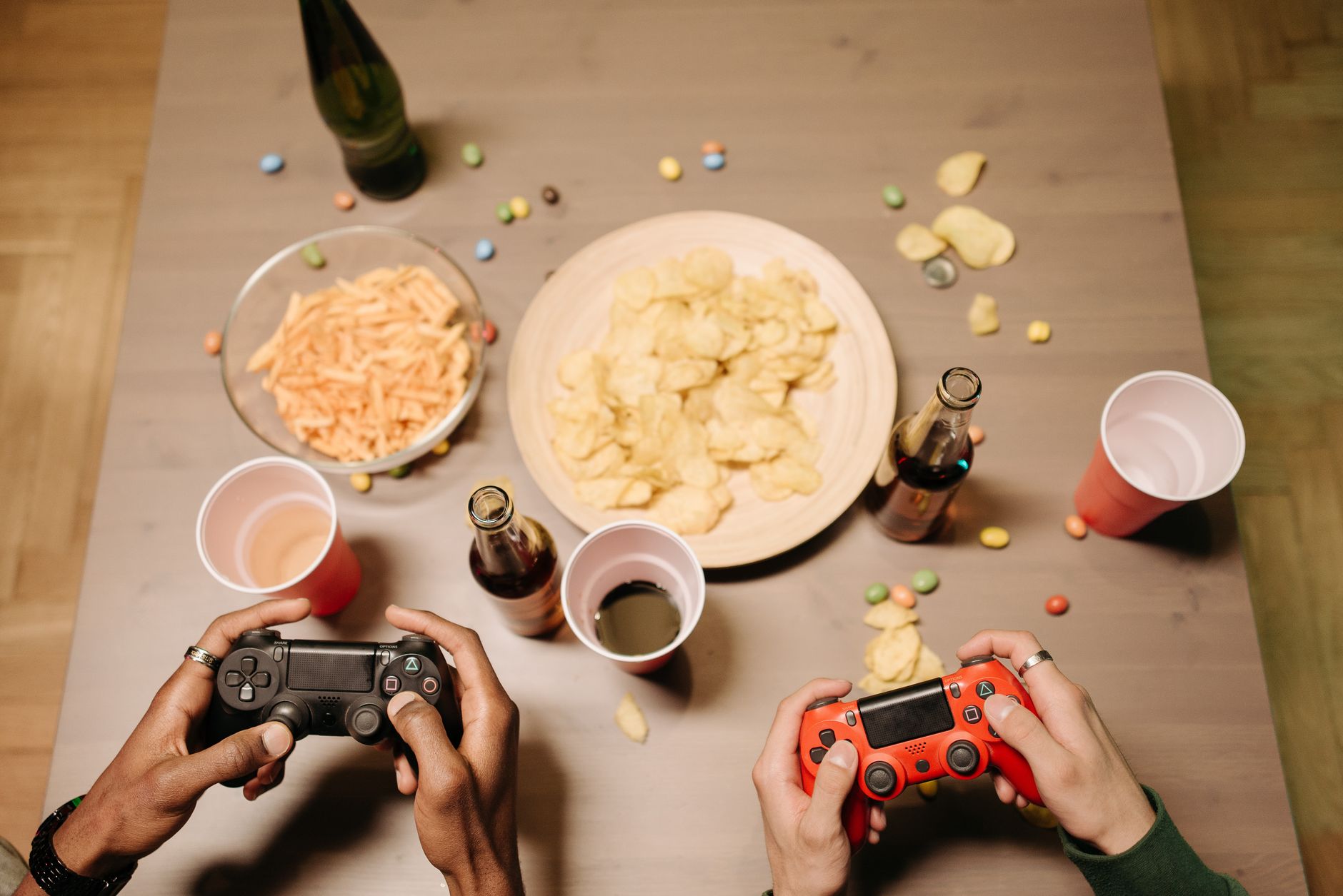 Two gamers playing video games with snacks and drinks on table, a perfect setup for gaming night. — Take Advantage of Generou