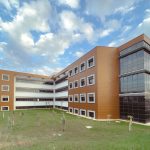 A modern educational building with a grassy lawn and partly cloudy sky. — Tantric Massage - Relax and Experience a Sensual Ex