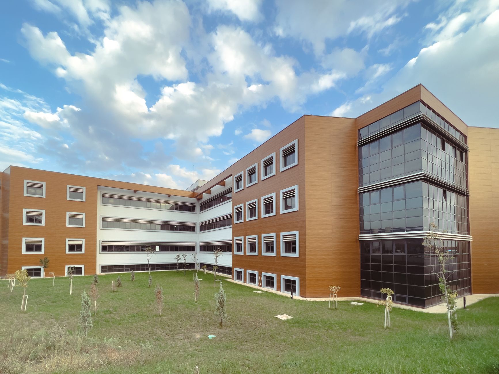 A modern educational building with a grassy lawn and partly cloudy sky. — Tantric Massage - Relax and Experience a Sensual Ex