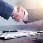 Professional handshake agreement over business charts in an office setting. — The Evolution of Cannabis Delivery: Exploring T
