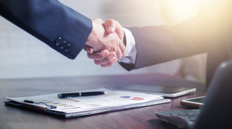 Professional handshake agreement over business charts in an office setting. — The Evolution of Cannabis Delivery: Exploring T