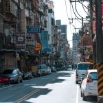 A busy street lined with cars and various colorful business signs on a sunny day. — The Role of Online Audio Mastering in Mod