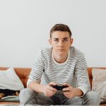 Teen boy intensely focused on video games at home, relaxing on a couch. — The way to Earn Profit With Online Gambling establi