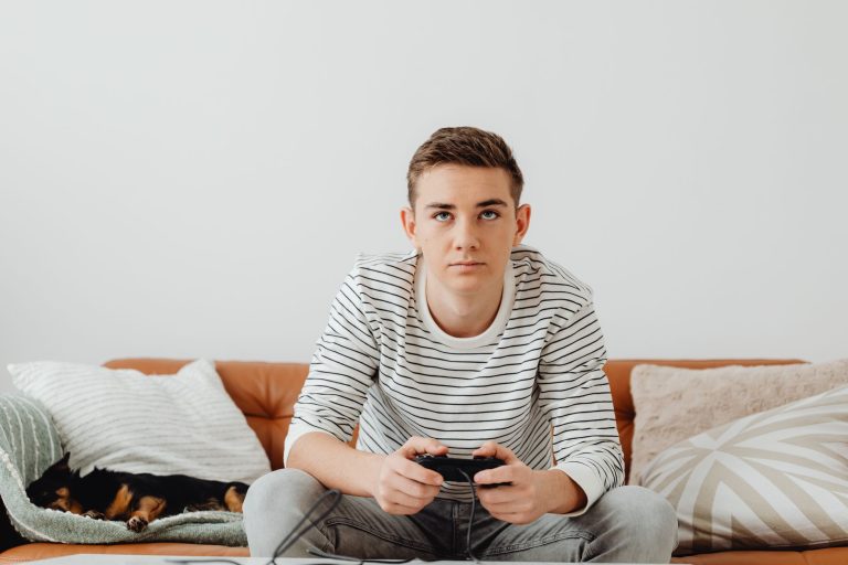 Teen boy intensely focused on video games at home, relaxing on a couch. — The way to Earn Profit With Online Gambling establi