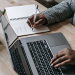 Crop unrecognizable African American female in formal wear writing notes in notepad while working on laptop — Tips for Findin