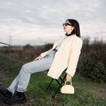 A stylish woman in sunglasses relaxes on a chair by a bridge in nature. — Tips on Maintaining and Cleaning a Weed Filter for