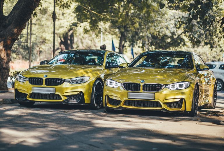 Two luxury BMW cars parked under trees in New Delhi on a sunny day. — Tips to Appoint An Auto Locksmith for Reprogramming the
