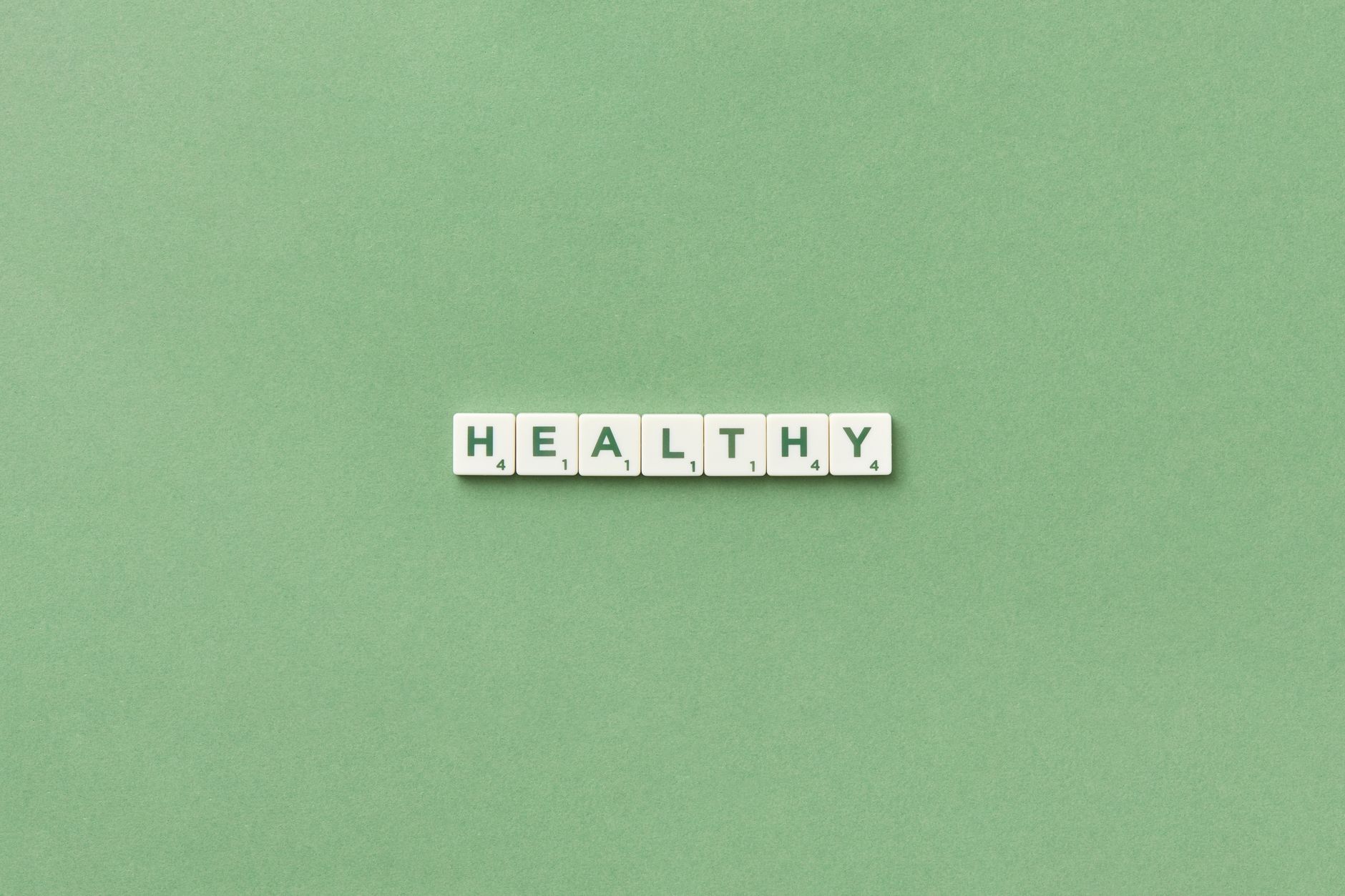 Scrabble tiles spelling the word 'healthy' on a light green background, top view. — Types of Intermittent Fasting