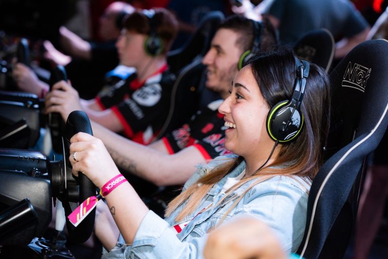 A group of people enjoying an immersive gaming experience at an e-sports center with headphones and steering wheels. — Use th