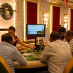 A group of adults playing at a casino table in Goa, India, captured indoors with festive decor. — Various details that you ha