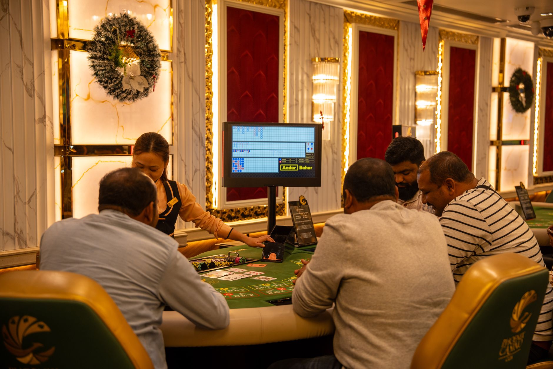 A group of adults playing at a casino table in Goa, India, captured indoors with festive decor. — Various details that you ha