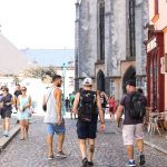 A bustling stone road in a historic European city filled with tourists enjoying a summer day. — Watch the Rare Japanese Anima