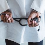A medical professional holding a stethoscope in a clinical setting. — What are the 5 points of auscultation?