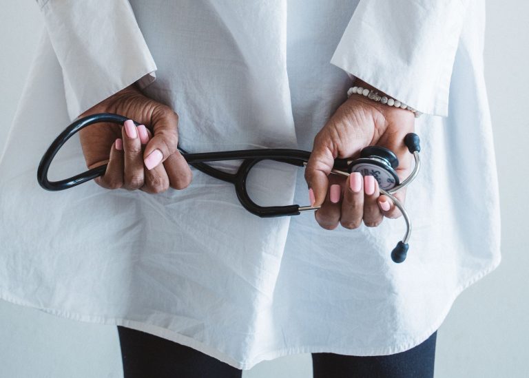 A medical professional holding a stethoscope in a clinical setting. — What are the 5 points of auscultation?