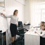 A female teacher guiding two girls during a lesson in a bright classroom with a whiteboard. — What are the various steps of s