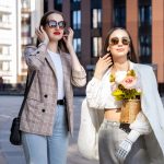 Two stylish women enjoy a sunny day in the city wearing chic outfits and sunglasses. — What do you mean by fingerprint jewelr