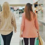 Two women walking in a mall holding shopping bags, back view. — What's the Best Way to Stay on Top of UK Hot Deals?