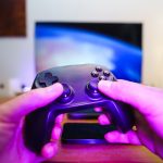 Close-up of hands holding a game controller in front of a TV screen. Perfect for entertainment setups. — Why does the person