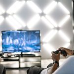 Two adults are having fun playing video games in a stylish, modern living room with LED lighting. — Why Igni Online Casino To