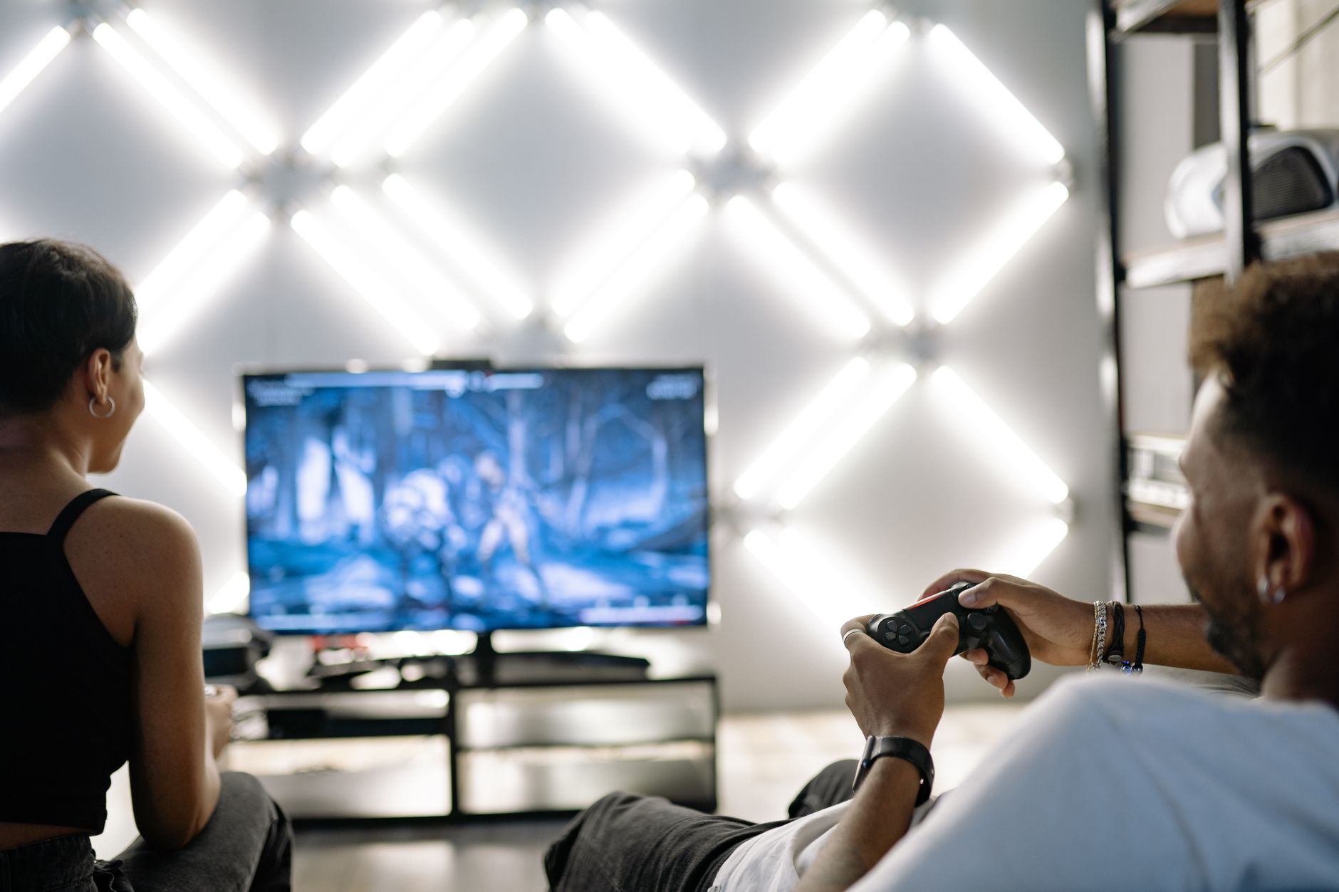 Two adults are having fun playing video games in a stylish, modern living room with LED lighting. — Why Igni Online Casino To