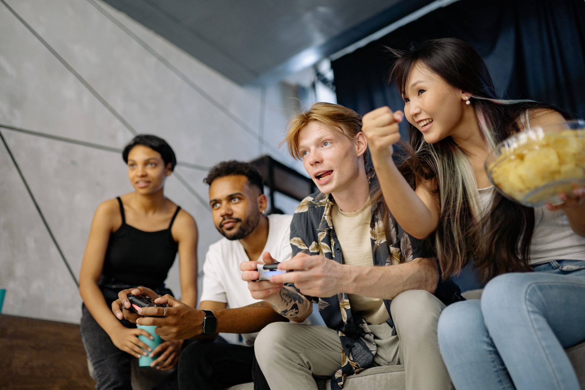 Four friends gaming enthusiastically inside a modern home, enjoying a lively moment. — Why Play The Online Lottery On Ligaz88